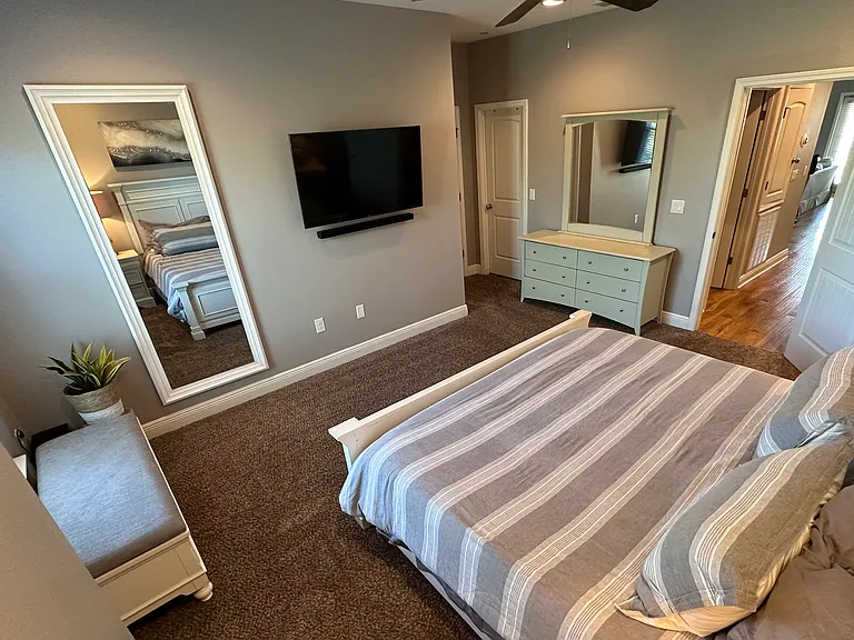 Master Bedroom with King bed, blackout curtains, dresser, and day bench! Lots of storage and space
