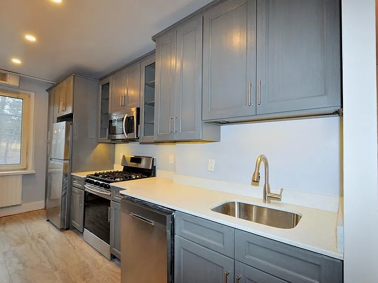 Renovated Kitchen with center Island, pendent lighting, Granite Counters, Stainless Steel Appliance including a dishwasher, range, microwave and refrigerator. The wall separating the eat-in-kitchen and living room have been removed and a center Island ins