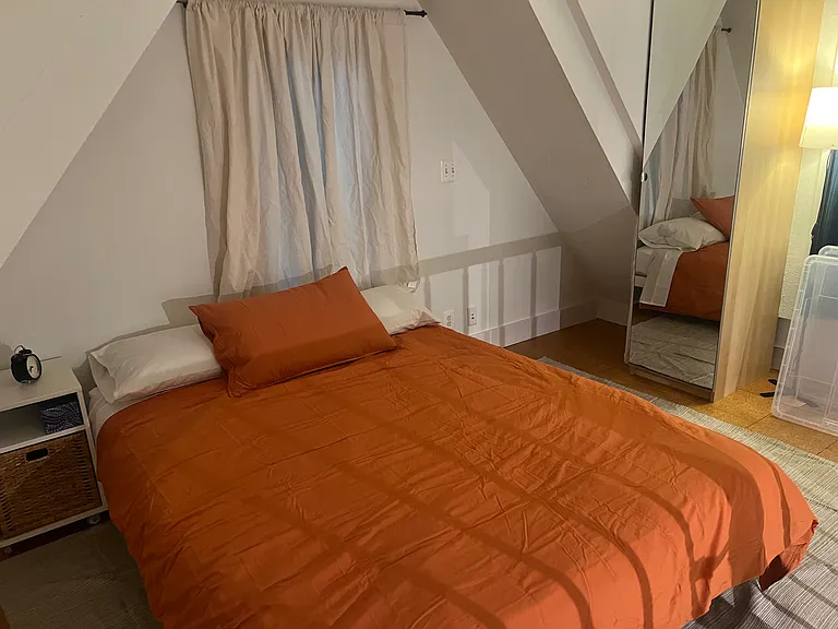 Newly furnished queen loft bedroom with new mattress, bedding, nightstand, lighting, workspace, and ample storage.