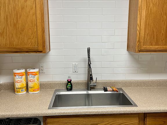 New refinished cabinets with new subway backsplash tile and Kohler commercial grade sink and faucet.