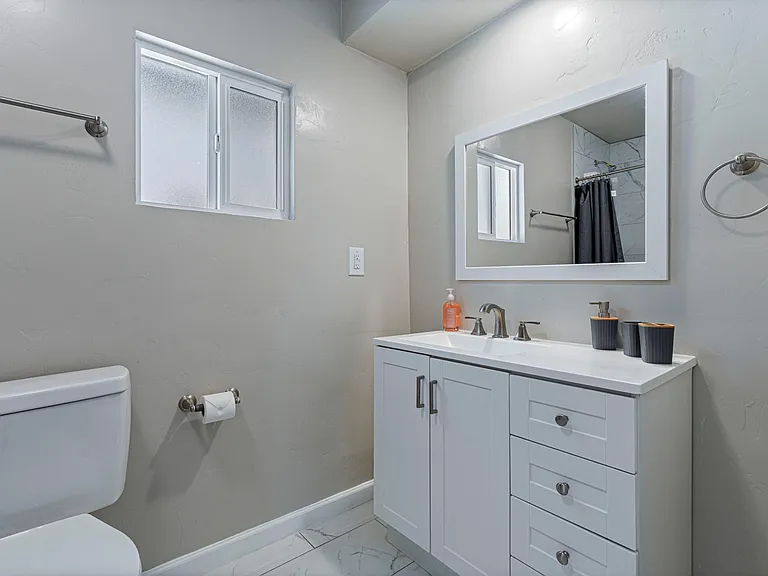 Updated bathroom with a spacious vanity, large framed mirror, and frosted window for privacy and natural light.