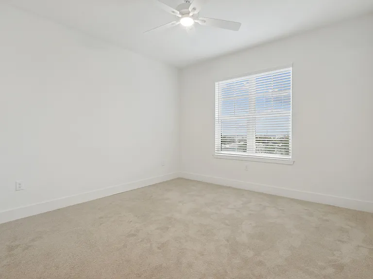 Inviting room with plush carpet, bright window, and ceiling fan, perfect for a tranquil home setting.