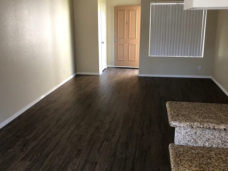 Kitchen view of living room and front enterance with large window for great natural light at Plaza Verde Apartments in Escondido, California.