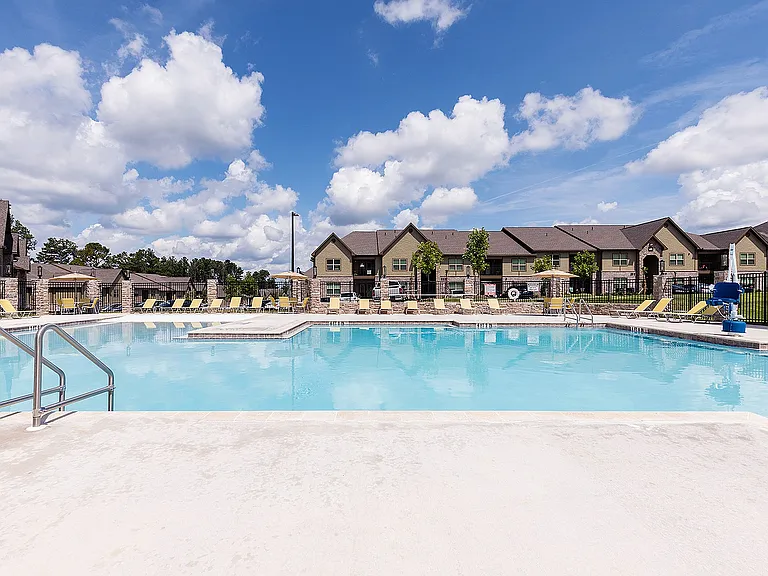 Inviting, large sparkling pool, surrounded by comfortable lounge chairs and framed by a beautiful blue sky.