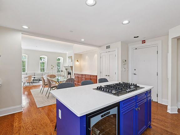 Full kitchen view with blue cabinetry, white quartz counters, and hardwood floors.