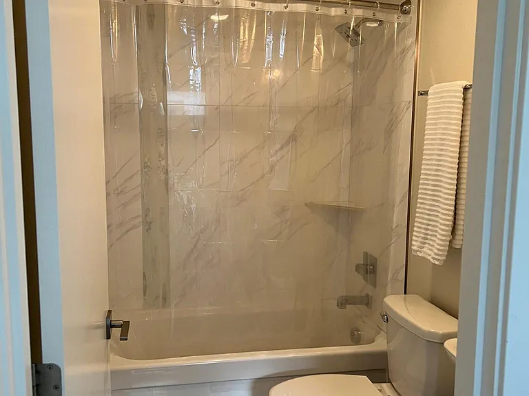 Guest bedroom in-suite bathroom with tub, shower, heated floor, and automatic exhaust fan.
