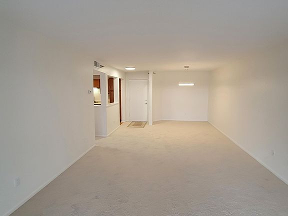 Main condo entrance door, living room, dining room, and kitchen to the right. Note brand new carpet.