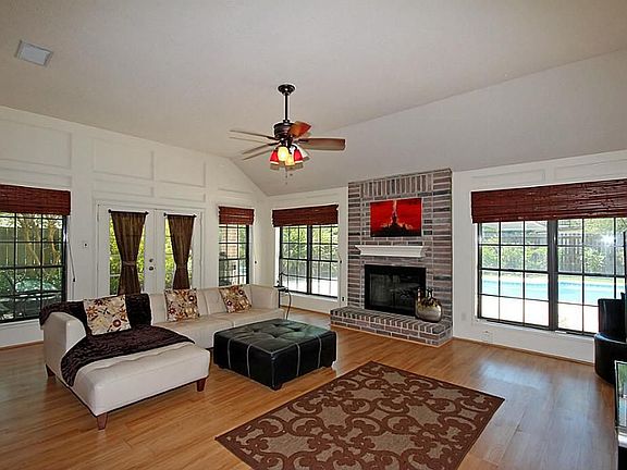 SPACIOUS DEN FEATURES WOOD FLOOR LAMINATE, DECORATIVE WOOD BORDERING CONTOURS THE WALLS FOR ELEGANCE