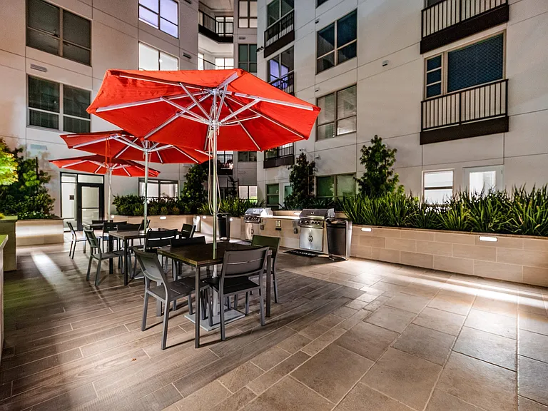 Outdoor dining area with grills, red umbrellas, and seating