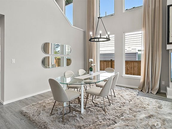 The open-concept living room offers ample space for a potential dining area, with a striking staircase that overlooks the space, adding a touch of architectural elegance.>