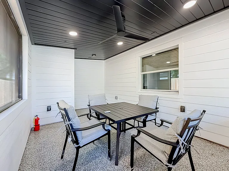 Spacious screened in patio with epoxy floor, wood ceiling fan and a table with four chairs to unwind after a hard day of work, park fun or visiting family.