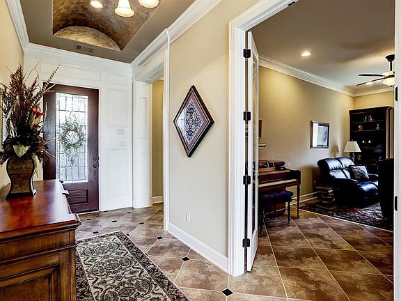 Inviting custom tiled entry with high ceilings. Custom painted ceilings and molding featured.