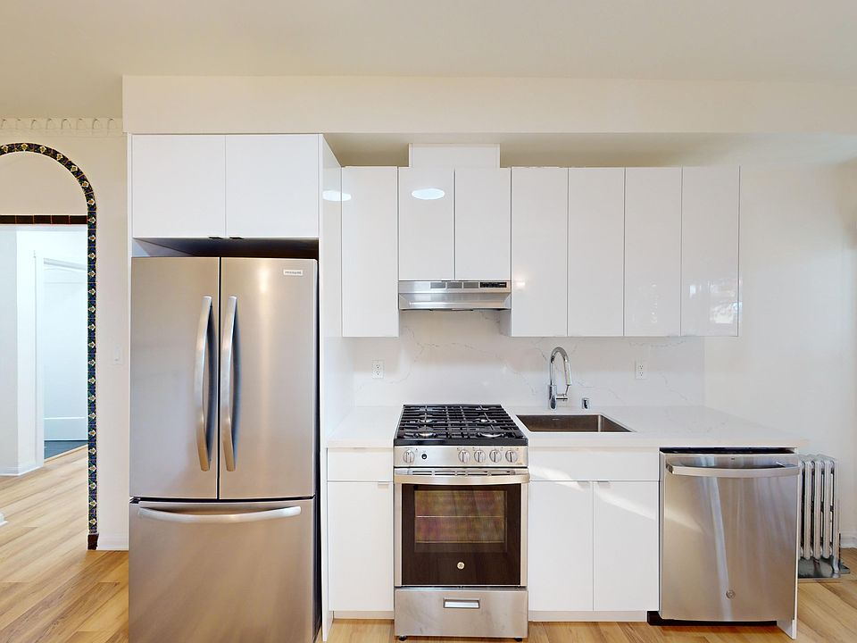 Kitchen with cabinets, refrigerator, stove, range hood, and sink
