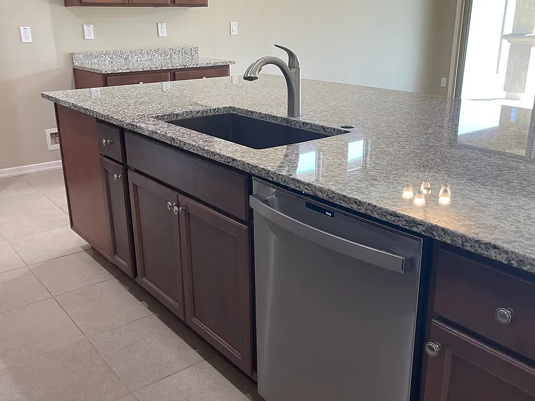 Front of kitchen island with large Blanco sink and upgraded GE dishwasher. Gigantic island area.