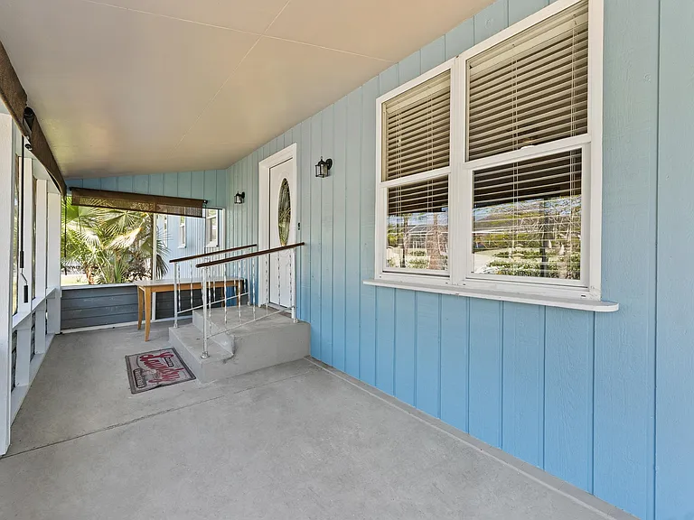 Covered front porch with screened panels, concrete flooring, and a private entry landing with exterior lighting.