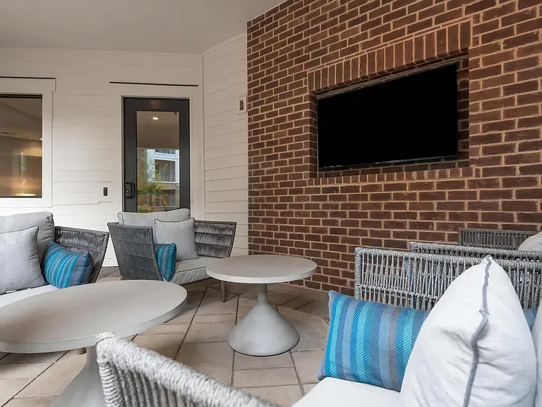 Cozy Outdoor Seating Area with Mounted TV and Modern Furniture