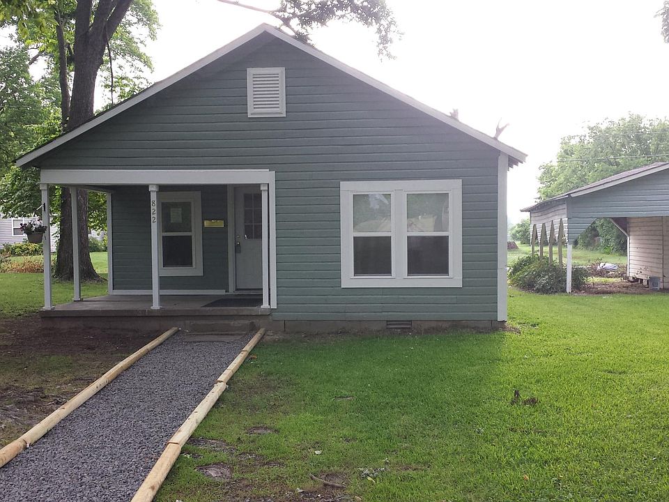 Front of home with a storage area and carport.