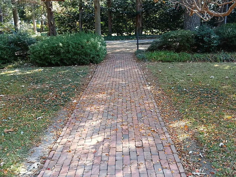 The front walkway includes a shaded gravel parking area and rustic countryside split-rail fencing.