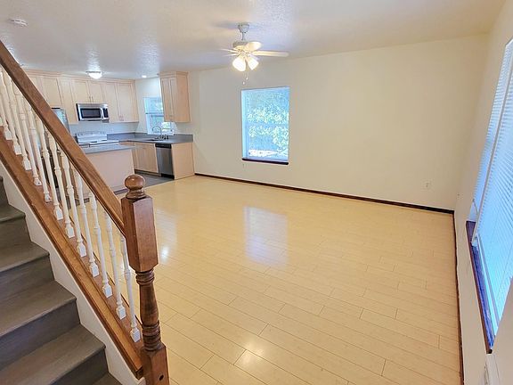 Living room with view of ceiling fan and stairs