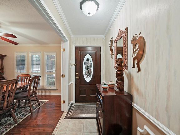 Foyer with crown molding, chair rail and tile floor. French doors open into the formal dining room.