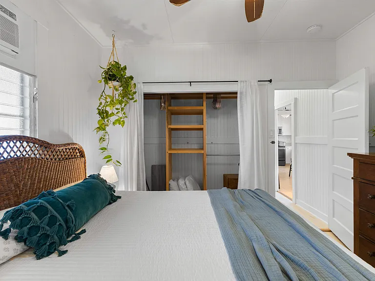 Front bedroom with queen bed, side tables, dresser, AC, ceiling fan, window and large closet with built-in shelving. French doors open to enclosed lanai.