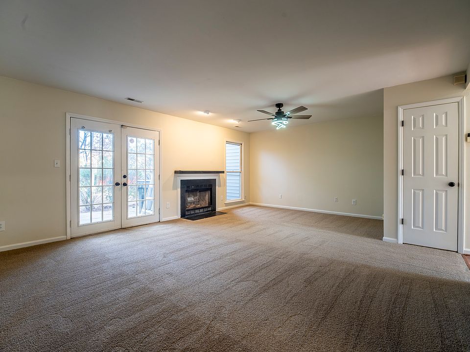 Large living room with fireplace, ceiling fan, and French doors leading to the private patio.