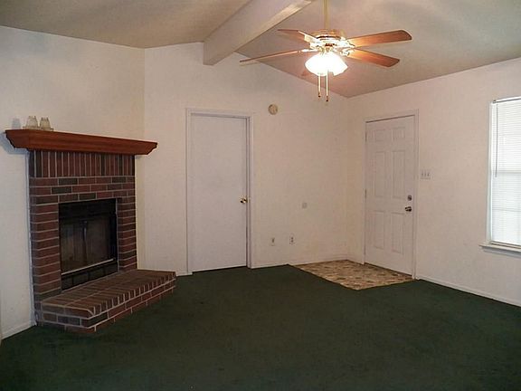 Living room has high ceilings & a wood burning fireplace
