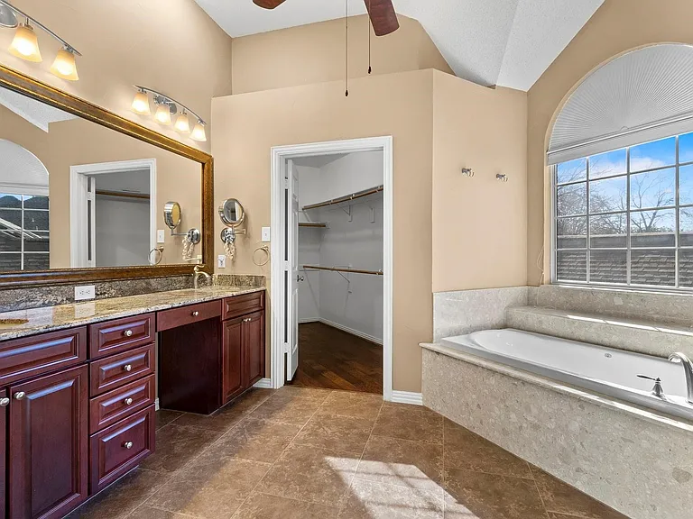 Spacious bathroom featuring a dual vanity with a stone countertop, dark wood cabinetry, and a large framed mirror