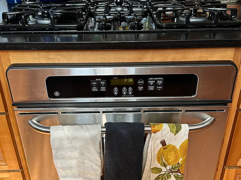 Island gas cooktop with electric oven with drawer storage and black granite countertop plus under counter plugs.