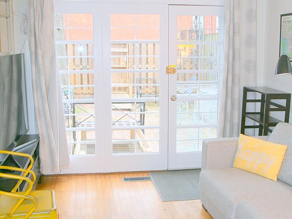 Living/Dining Room: wood floors, sleeper sofa, TV, dining set, and blackout linen curtains.
