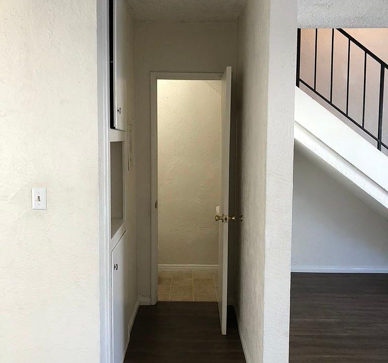 hallway to 1/2 bath with storage cabinets