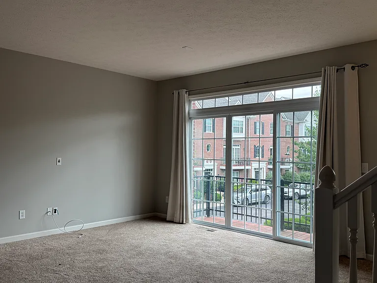 On the second floor is a large living room with sliding doors out onto an outdoor deck overlooking manicured common areas with benches and community space.