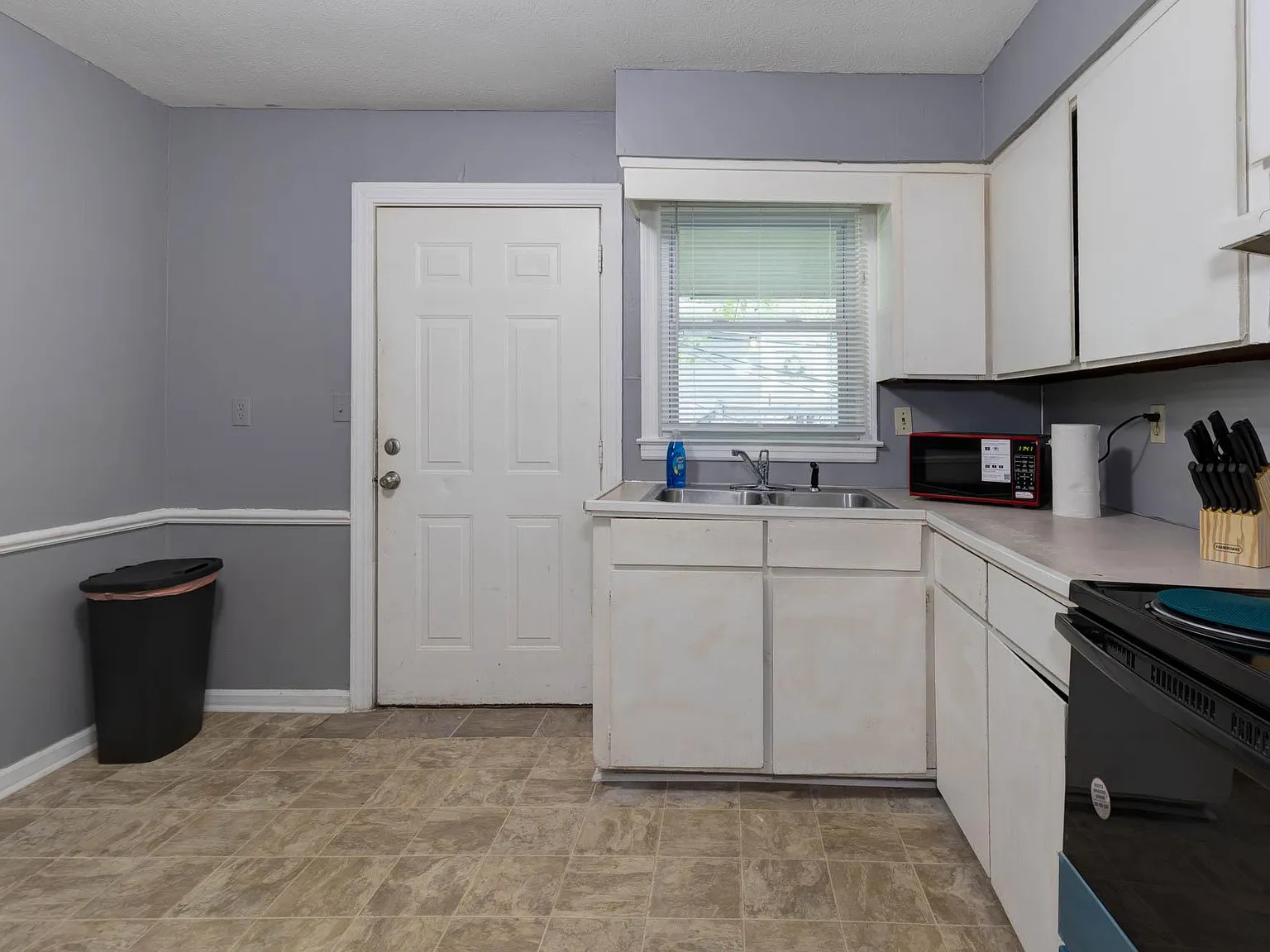 Efficient kitchen with ample cabinet storage, durable counters, double sink, and a window over the workspace.