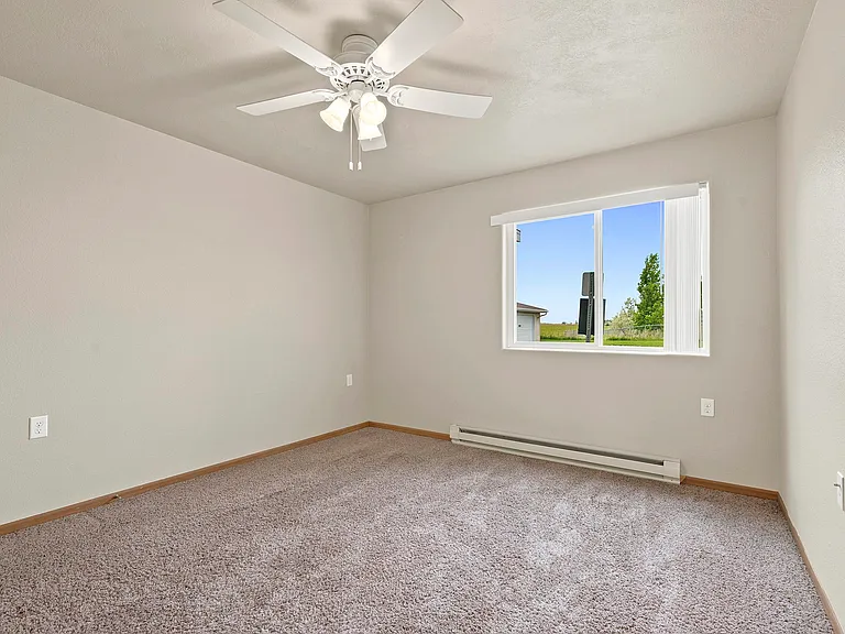Transform your living space at Northdale Apartments with this spacious, sunlit bedroom featuring plush carpeting and a large window. Ideal for relaxation or productivity, this room is designed for your lifestyle. Schedule a tour today!