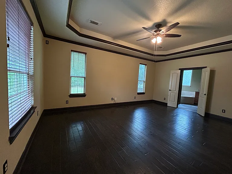 master suite is very large with hardwood floors, coffered ceilings, and blinds and right next to the laundry room for ease