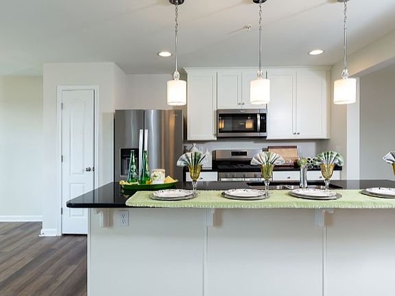 Kitchen with white cabinets, black countertops and stainless steel appliances.