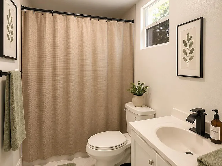 Full bathroom with single-sink vanity, tub/shower combo, and window for natural light; includes towel storage and tile floori