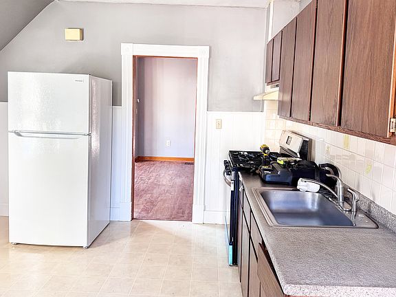 Kitchen with a brand new fridge and 5-burner gas stove.