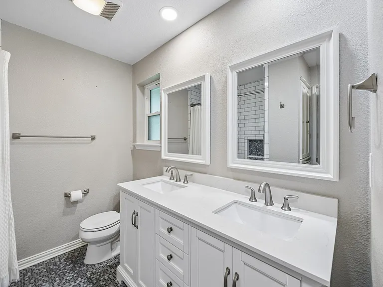 Double vanity featuring white cabinetry, integrated sinks, brushed nickel fixtures, and a white countertop