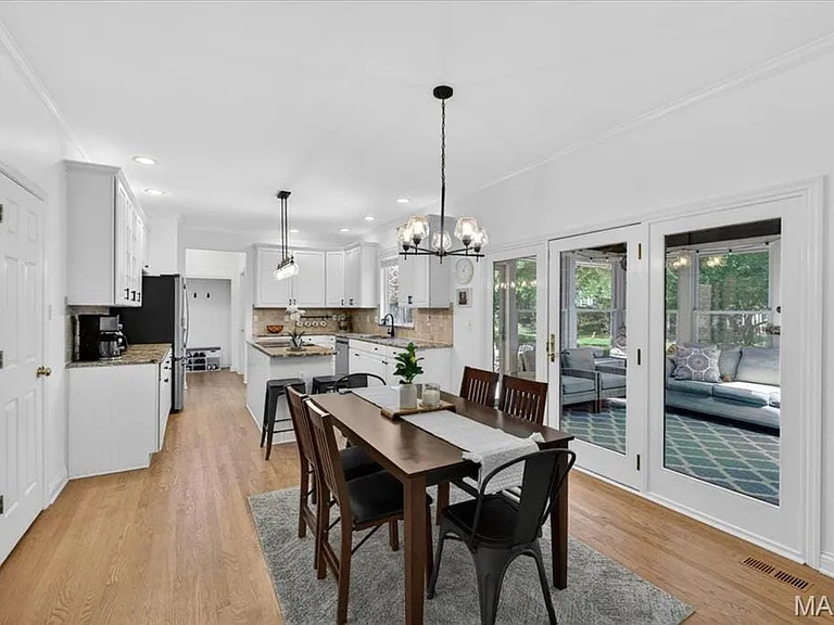 Open-concept kitchen and dining area featuring wood-finish flooring, white cabinetry, a kitchen island with seating, a tile backsplash, and recessed lighting
