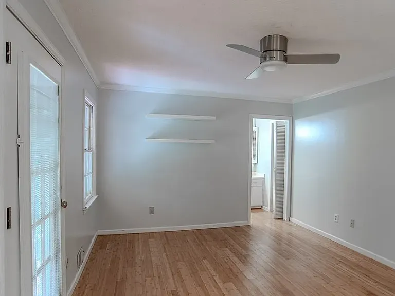 Large primary bedroom with hardwood floor, exit to screened porch, built-in shelves, large closet and ensuite bath