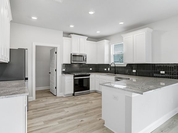 Chef-ready kitchen with stainless appliances, white cabinetry, and recessed lighting.