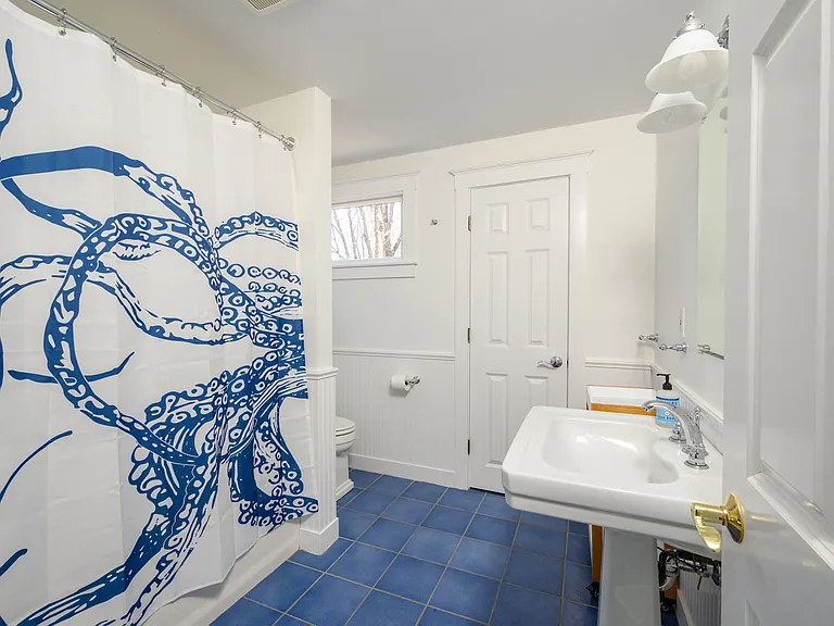 Second floor bathroom with bathtub shower, hair dryer, etc., servicing the two top left bedrooms.