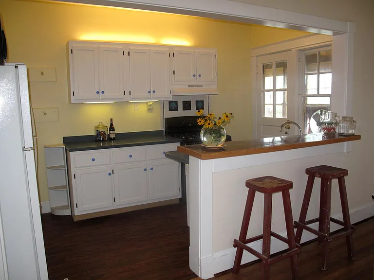 kitchen area, leading to back sunroom. Dishwasher, gas stove with custom tiled backsplash; passthrough ledge to dining room;
kitchen currently is newly painted--light teal green with vintage yellow bar stools