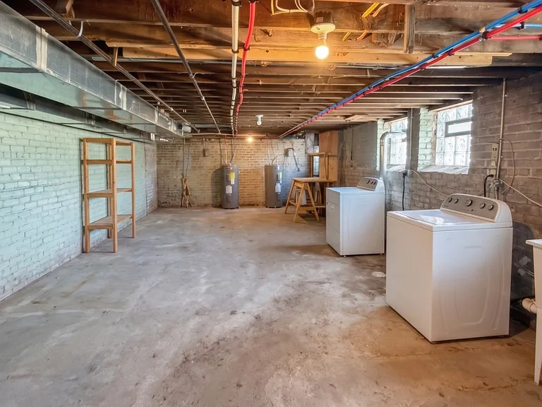 Basement with storage and clothes washer, dryer, and wash basin.