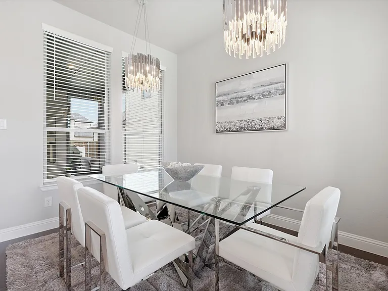 Dining area featuring two contemporary chandeliers and wood floors.