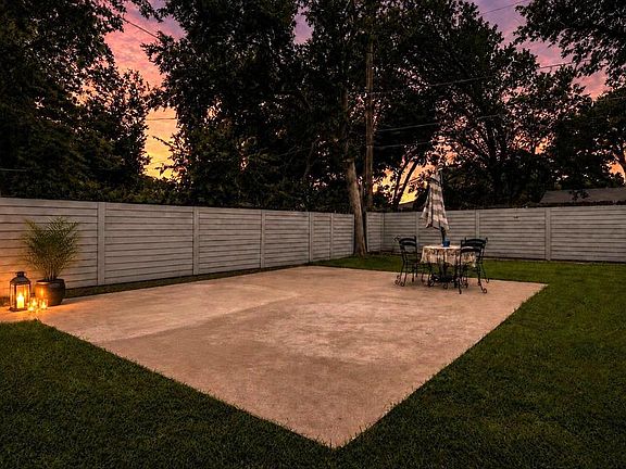 Expansive concrete patio bordered by a horizontal slatted privacy fence