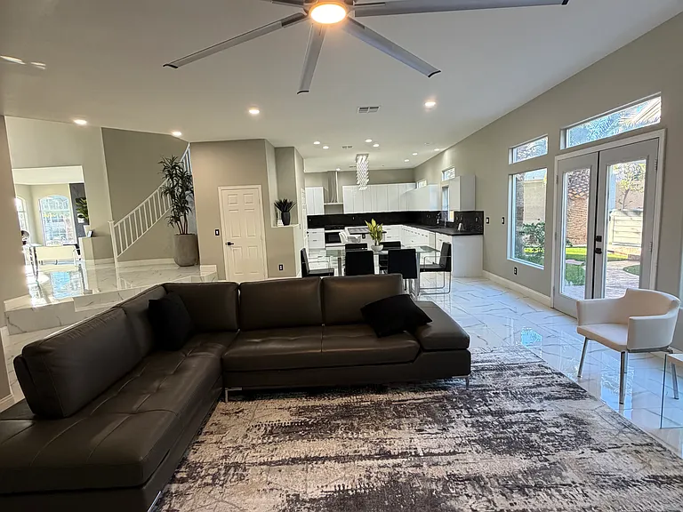 Open living area featuring an oversized ceiling fan, designer furnishings, and seamless flow to the dining space.
