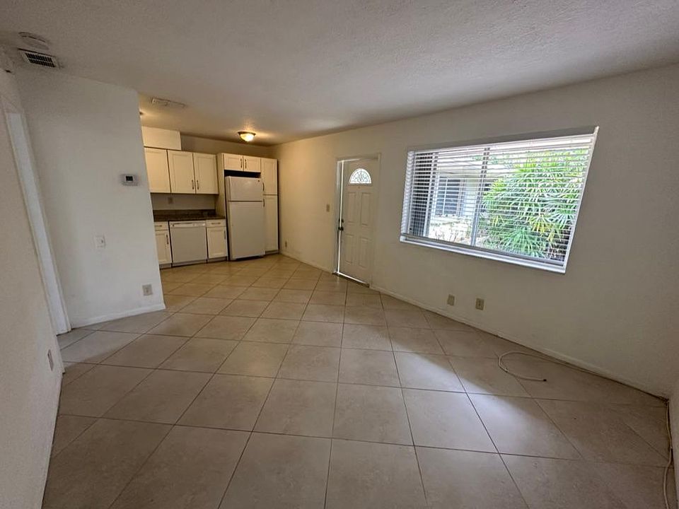 View form corner of living room to front window, entry door and kitchen in background