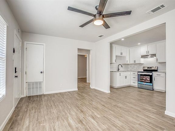 Kitchen featuring ceiling fan, electric stove, white cabinets, backsplash, and light wood-style flooring
